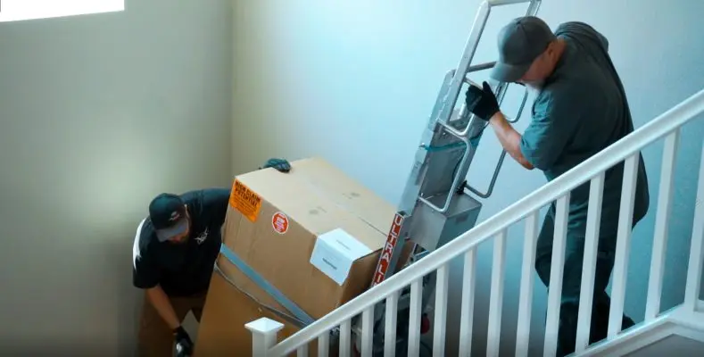 two men delivering a safe up a flight of stairs